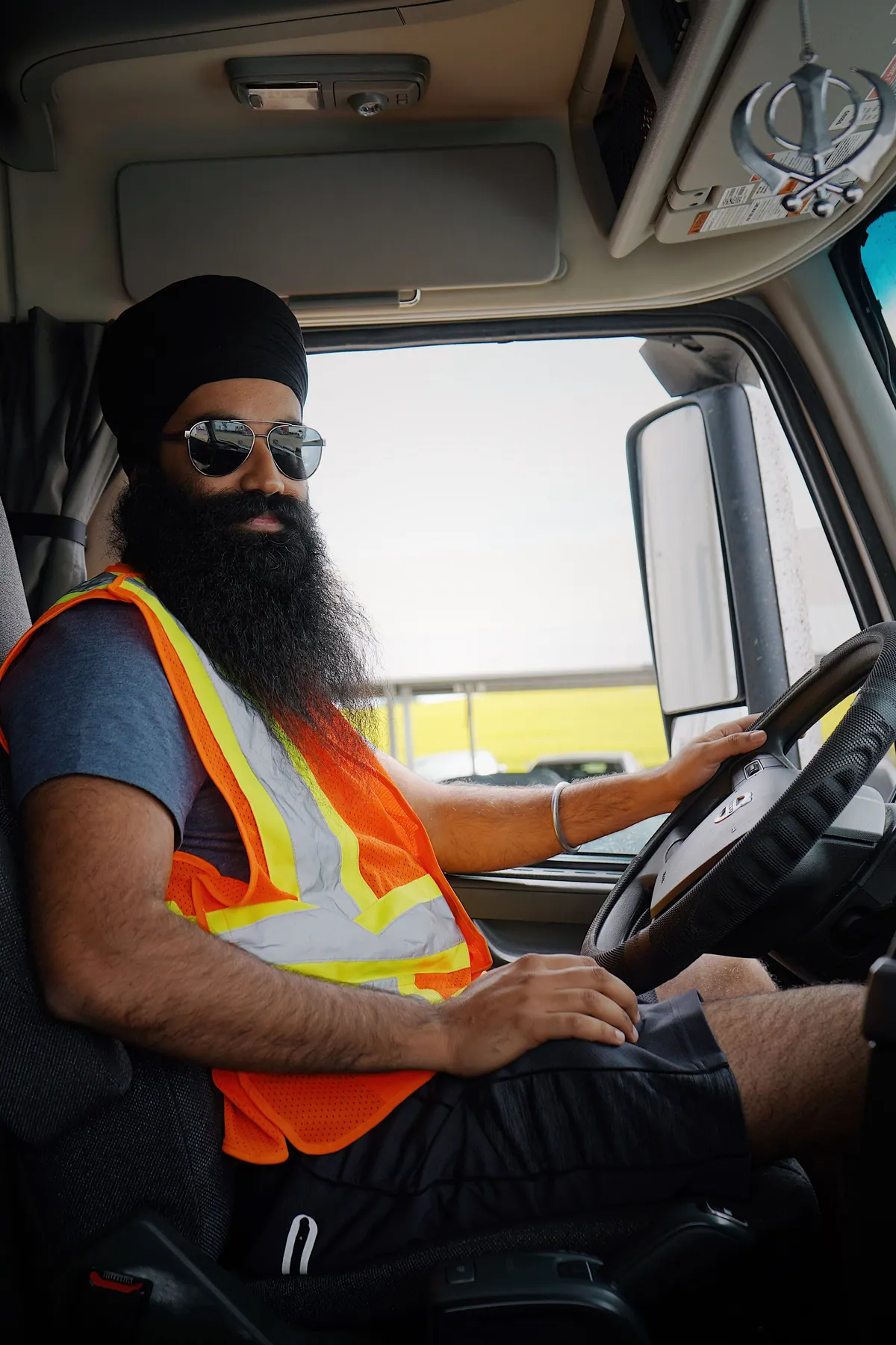 A truck driver in a hi-vis vest at the wheel