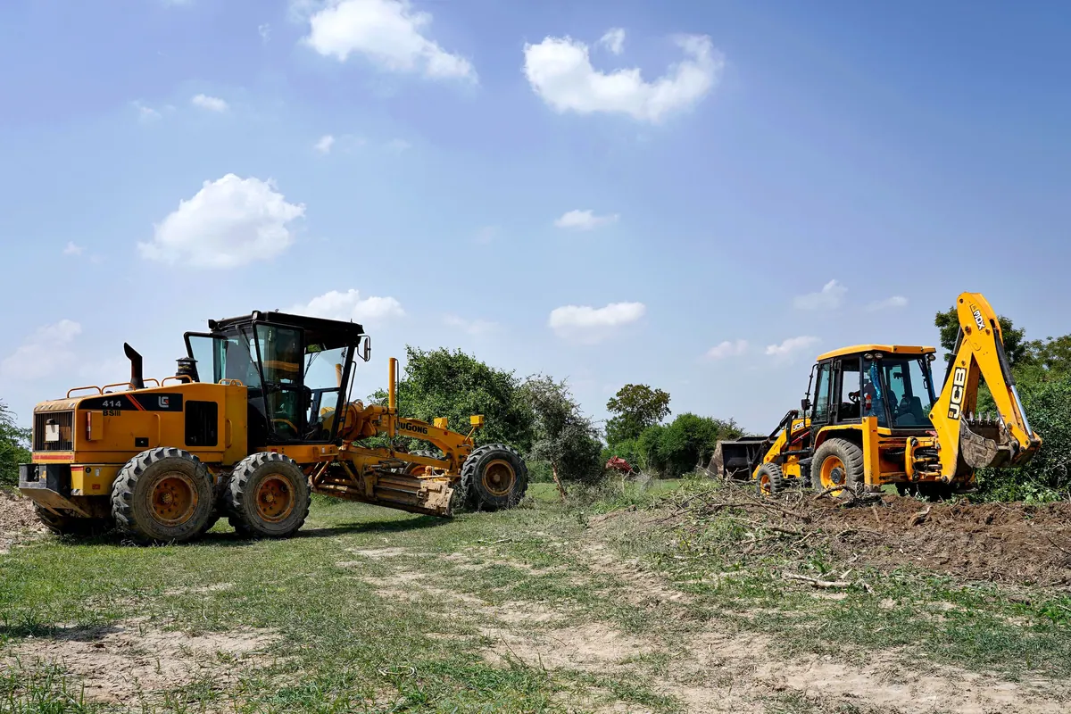 Two earthmovers working on open ground under a clear sky